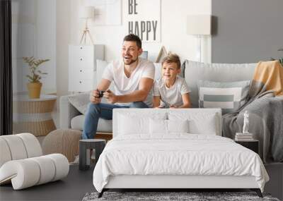 Father and his little son playing video games at home Wall mural