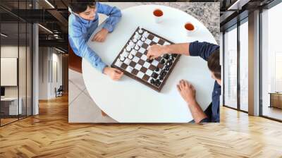 Father and son playing chess at home Wall mural