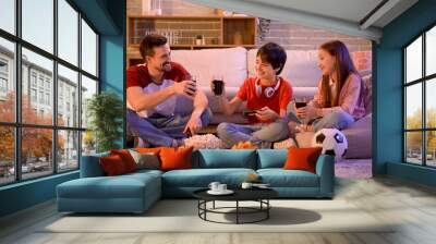 Father with his children drinking cola while playing video game at home in evening Wall mural