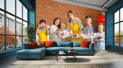 Female chef with group of little children and prepared pastry after cooking class in kitchen Wall mural