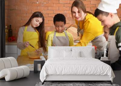 Female chef with group of little children preparing pizza during cooking class in kitchen Wall mural