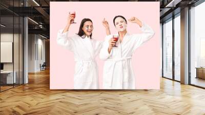 Female friends in bathrobes with facial mask and under-eye patches drinking wine on pink background Wall mural