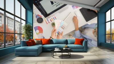 Female graphic designers working with color palettes at table in office, top view Wall mural