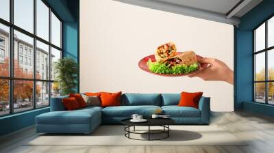 Female hand holding plate with tasty doner kebab on light background Wall mural