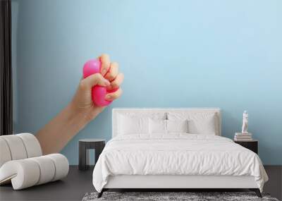 Female hand squeezing stress ball on color background Wall mural