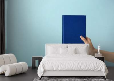 Female hand with book on color background Wall mural