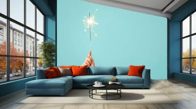 Female hand with Christmas sparkler on color background Wall mural