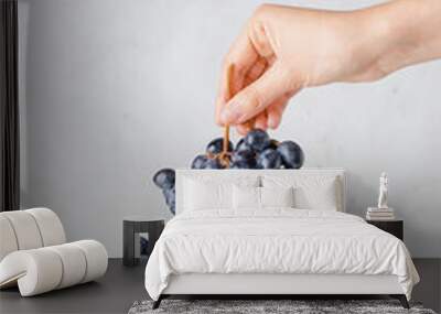 Female hand with fresh grapes and colander on light background Wall mural