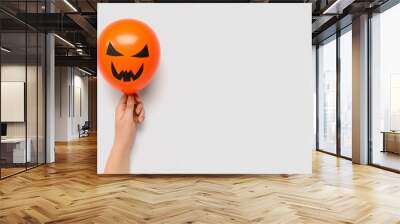 Female hand with funny Halloween orange balloon on white background Wall mural