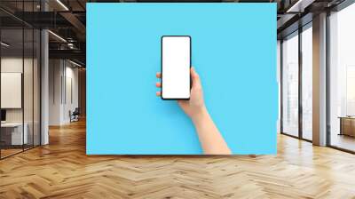 Female hand with modern mobile phone on blue background Wall mural