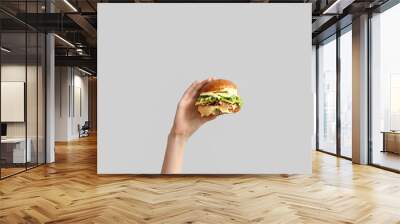 Female hand with tasty burger on white background Wall mural