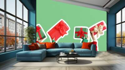 Female hands holding Christmas gift boxes on green background Wall mural