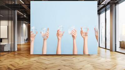 Female hands with glasses of water on color background Wall mural