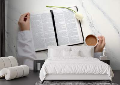 Female hands with Holy Bible, tulip flower and cup of coffee on white background Wall mural