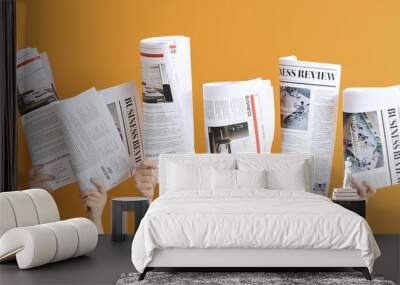 Female hands with newspapers on orange background Wall mural