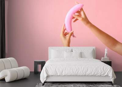 Female hands with pink banana on color background Wall mural