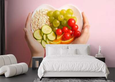 Female hands with plate and fresh healthy products on pink background. Diet concept Wall mural