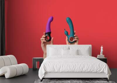 Female hands with vibrators on red background Wall mural