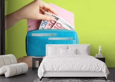 Female hands with wallet and money on color background Wall mural