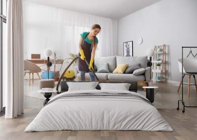 Female janitor with vacuum cleaner in room Wall mural