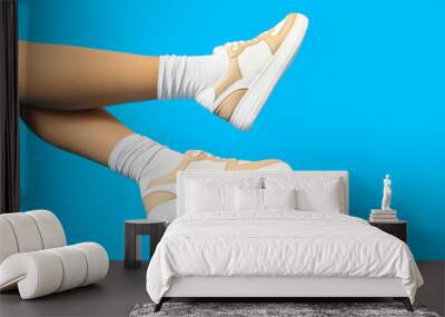 Female legs in stylish sneakers on color background, closeup Wall mural