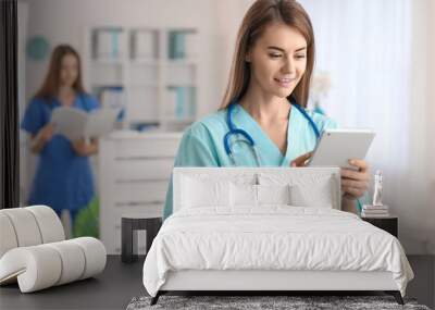 Female medical assistant using tablet computer in clinic Wall mural