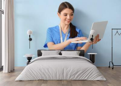 Female medical intern working with laptop on blue background Wall mural