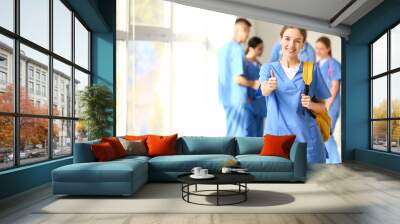 Female medical student showing thumb-up gesture in hall of clinic Wall mural