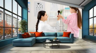 Female ophthalmologist with occluder and little girl in clinic Wall mural