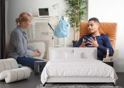 Female psychologist working with teenage boy in office Wall mural