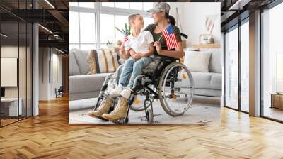 Female soldier and her little son with USA flags in wheelchair at home Wall mural