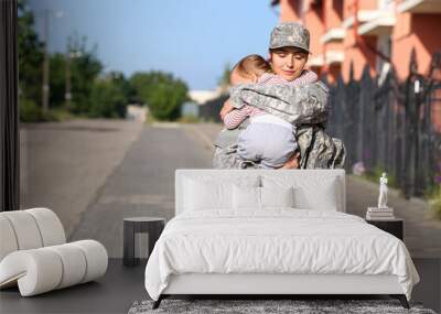 Female soldier with her little daughter outdoors Wall mural