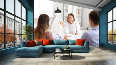 Female wedding planner discussing ceremony with clients in office Wall mural