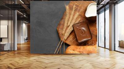 Fresh bread with tasty chocolate butter and jug of milk on dark background with space for text Wall mural