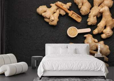 Fresh ginger roots, wooden scoops and spoon with dried powder on black background Wall mural