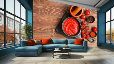 Frying pan of tomato sauce and bowl with peppercorn on wooden background Wall mural