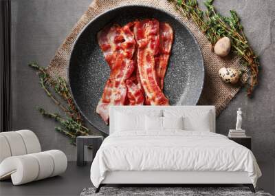 Frying pan with tasty bacon on grey background Wall mural