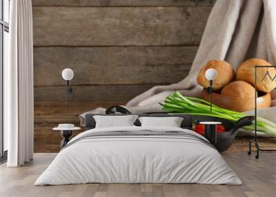 Frying pan with tasty eggs, tomatoes, green onion and buns on wooden table Wall mural