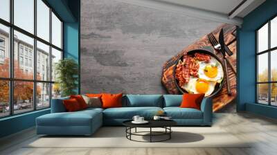 Frying pan with tasty eggs and bacon on grey background Wall mural