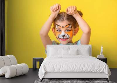 Funny little girl with face painting on color background Wall mural