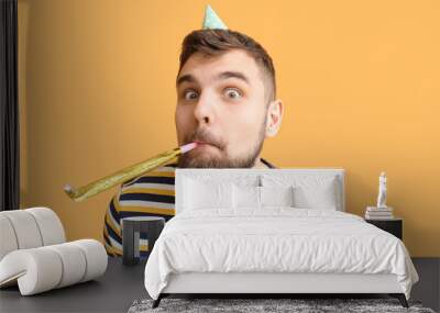 Funny man with party whistle celebrating Birthday on orange background Wall mural