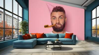 Funny portrait of man with Birthday hat and party whistle on color background Wall mural