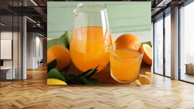 Glass and jug of fresh orange juice and fruits on white table Wall mural