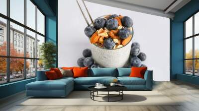 Glass of chia pudding with blueberries, nuts and oat flakes on light background Wall mural