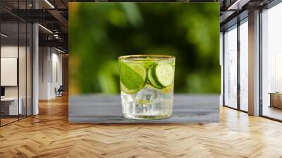 Glass of cucumber lemonade on table outdoors Wall mural