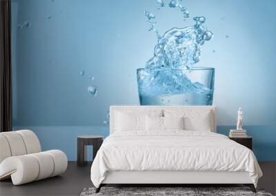 Glass of fresh water with splash on color background Wall mural