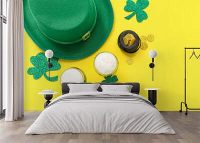 Glasses of beer with clover, coins and leprechaun hat on yellow background. St. Patrick's Day celebration Wall mural