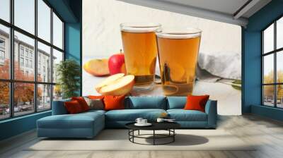 Glasses of fresh apple juice on light blue table Wall mural