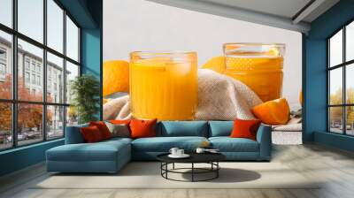 Glasses of tasty orange juice on light background Wall mural