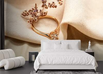 Golden engagement ring with flowers on beige fabric background, closeup Wall mural